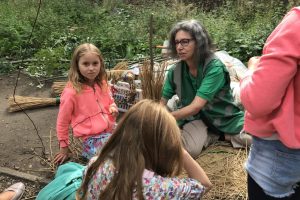 Elizabeth helping children make reed brooms